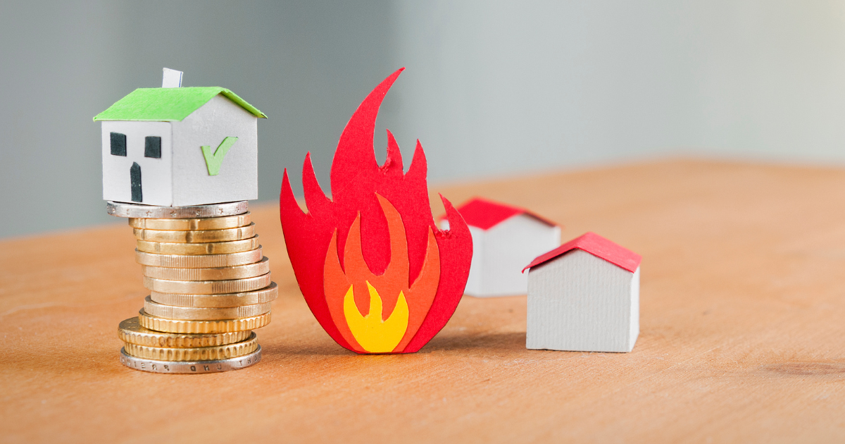 Paper homes close to fire, while a protected home rises above on coins - symbolizing the importance of fire insurance and its role in safeguarding investments