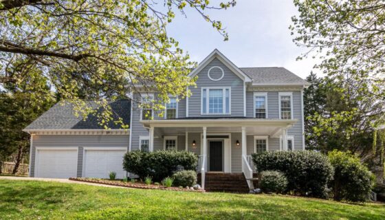 Gray two-story house with a porch and trees.