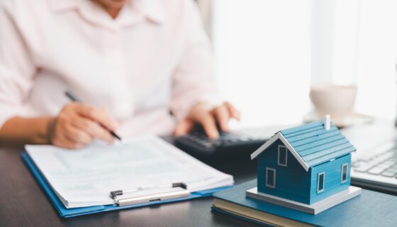 Person reviewing rental property documents and checking off items on a landlord annual checklist at a desk.